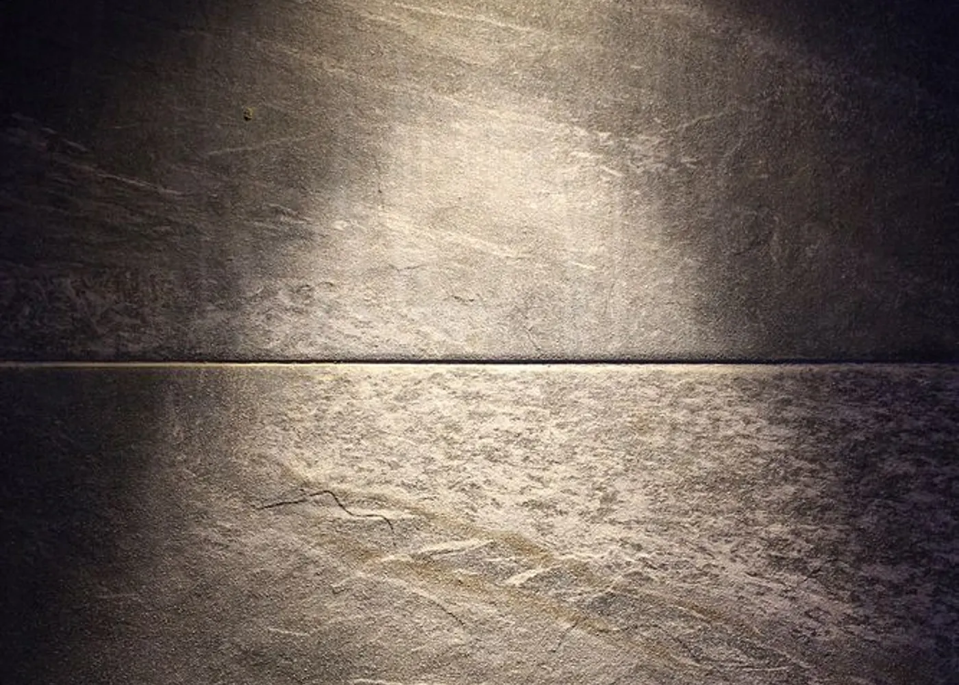 Morning light crossing a quiet plaster wall in an otherwise empty room.